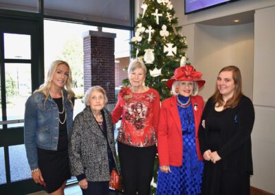 A group of women standing in front of a christmas tree.