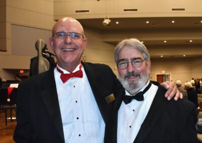 Two men in tuxedos posing for a photo.